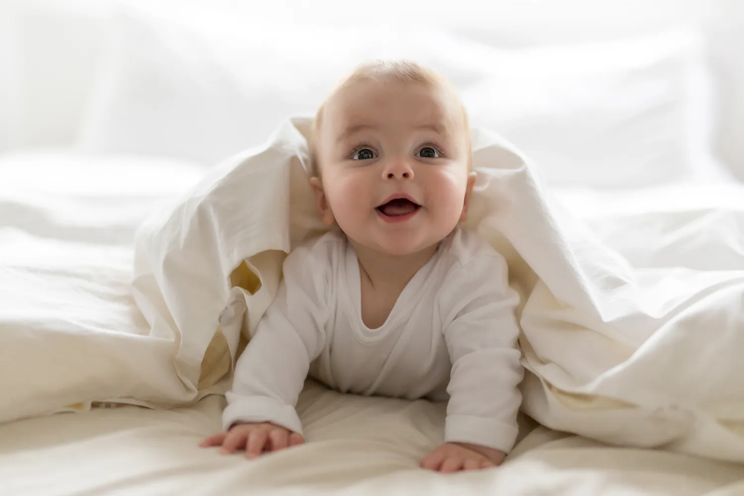 Smiling baby crawling under a blanket