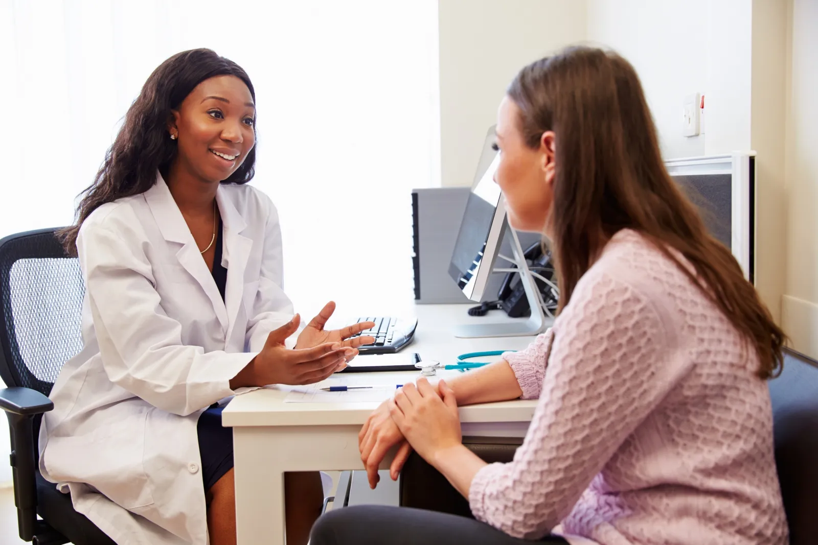 Woman doctor sitting at a desk talking to a woman
